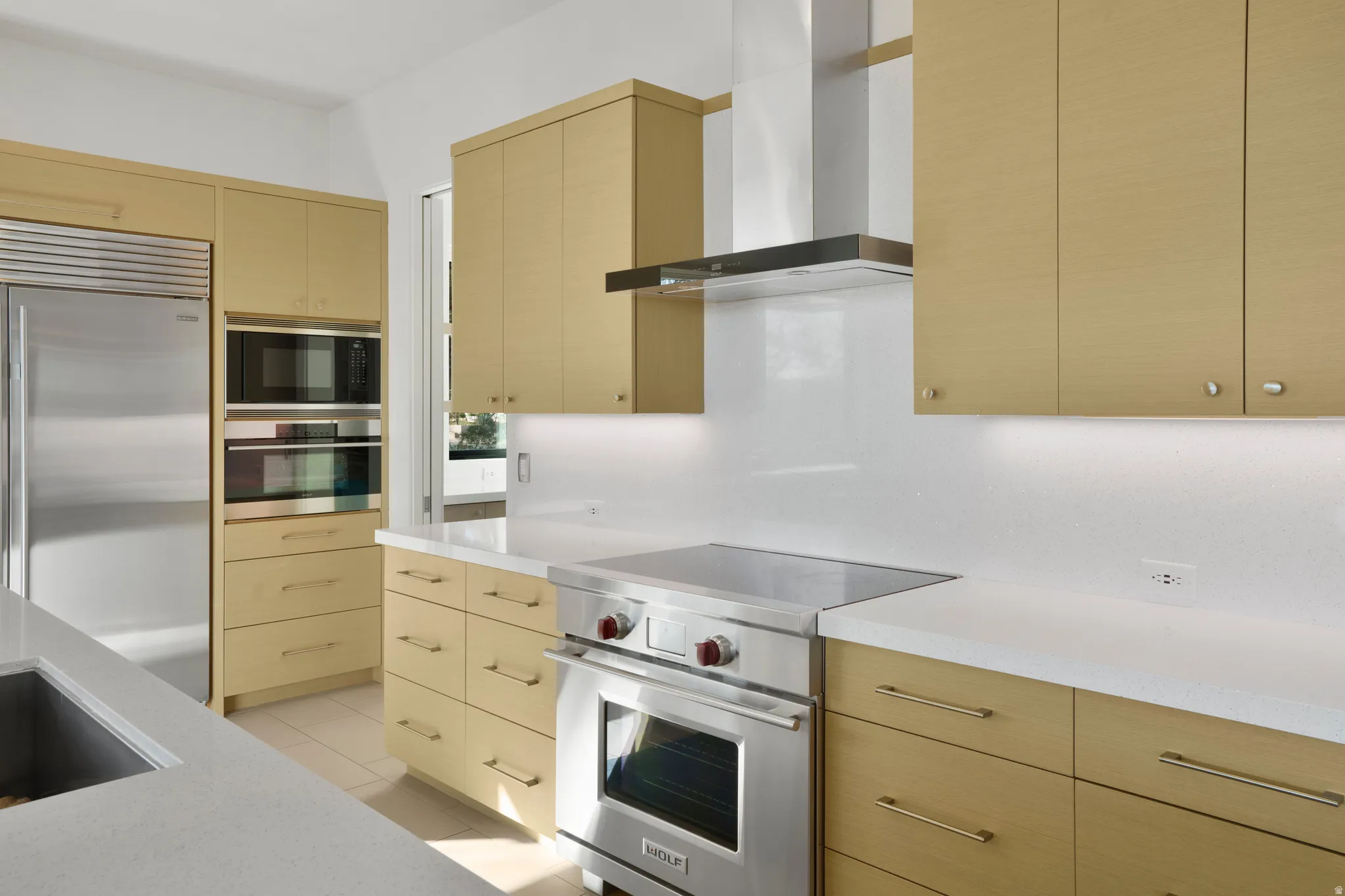 Kitchen featuring built in appliances, light tile patterned floors, light stone counters, and modern cabinets