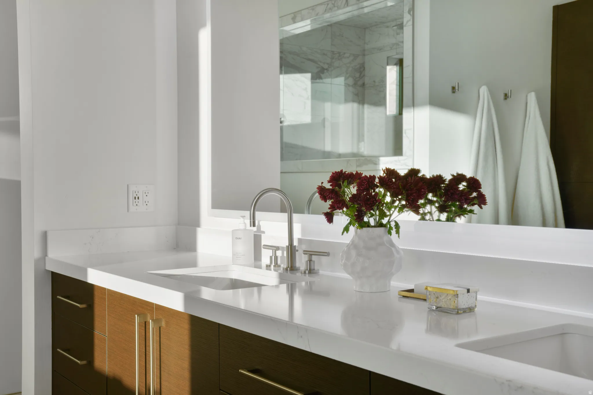 Full bath with double vanity and a marble finish shower