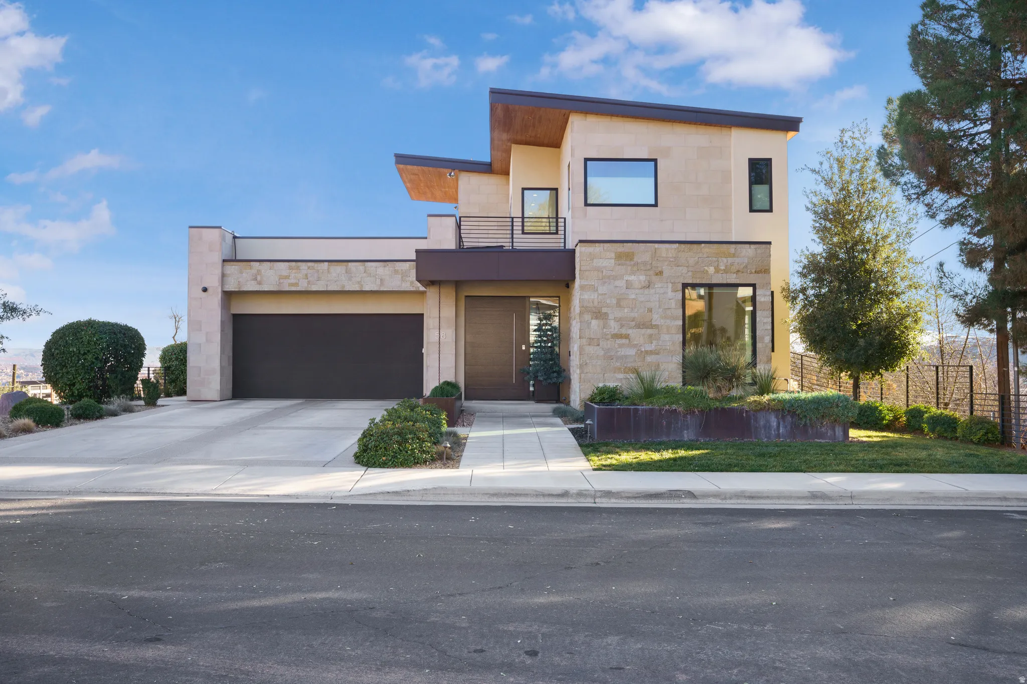 Contemporary house with stone siding, a balcony, and driveway