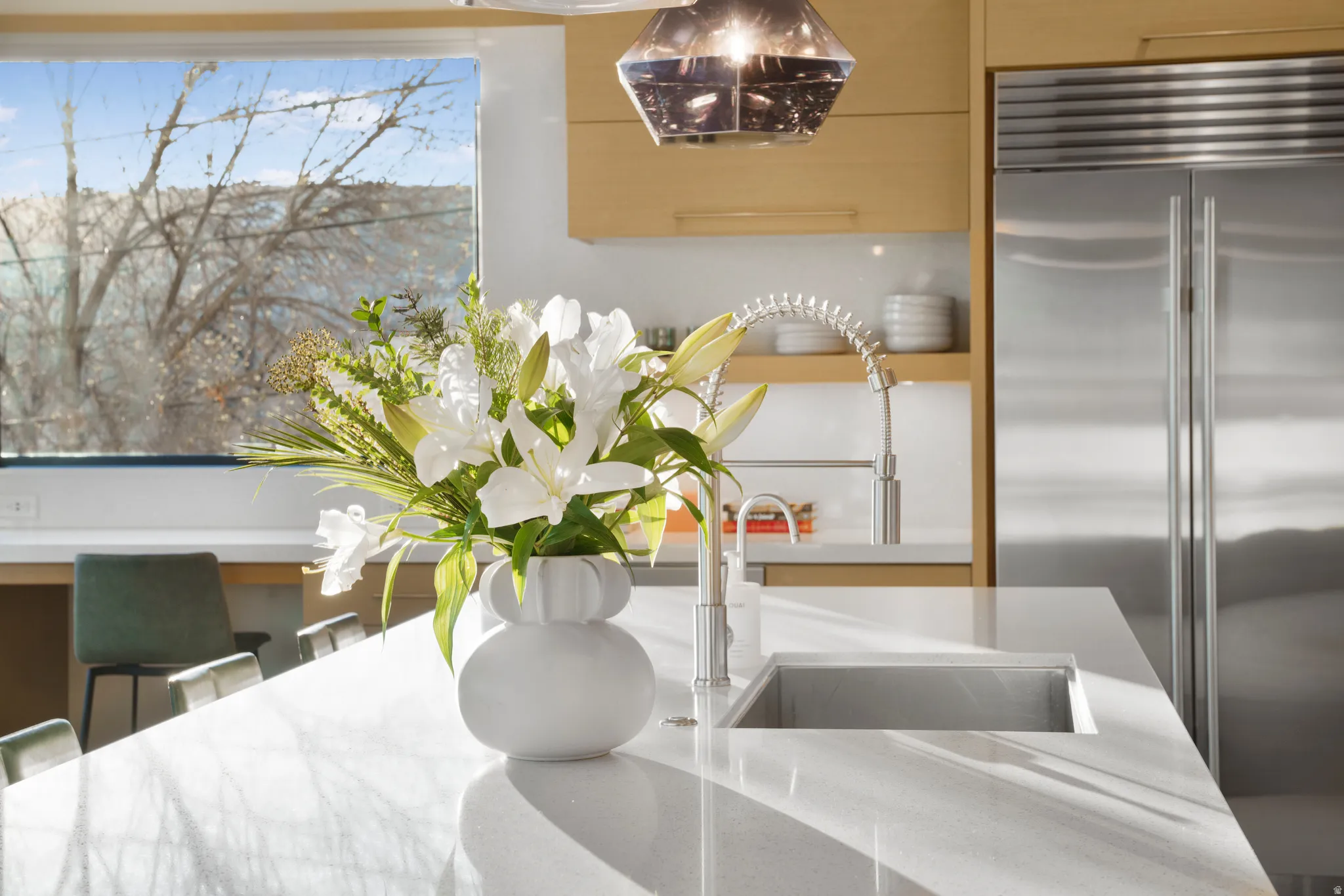 Kitchen view of built in fridge and light stone countertops