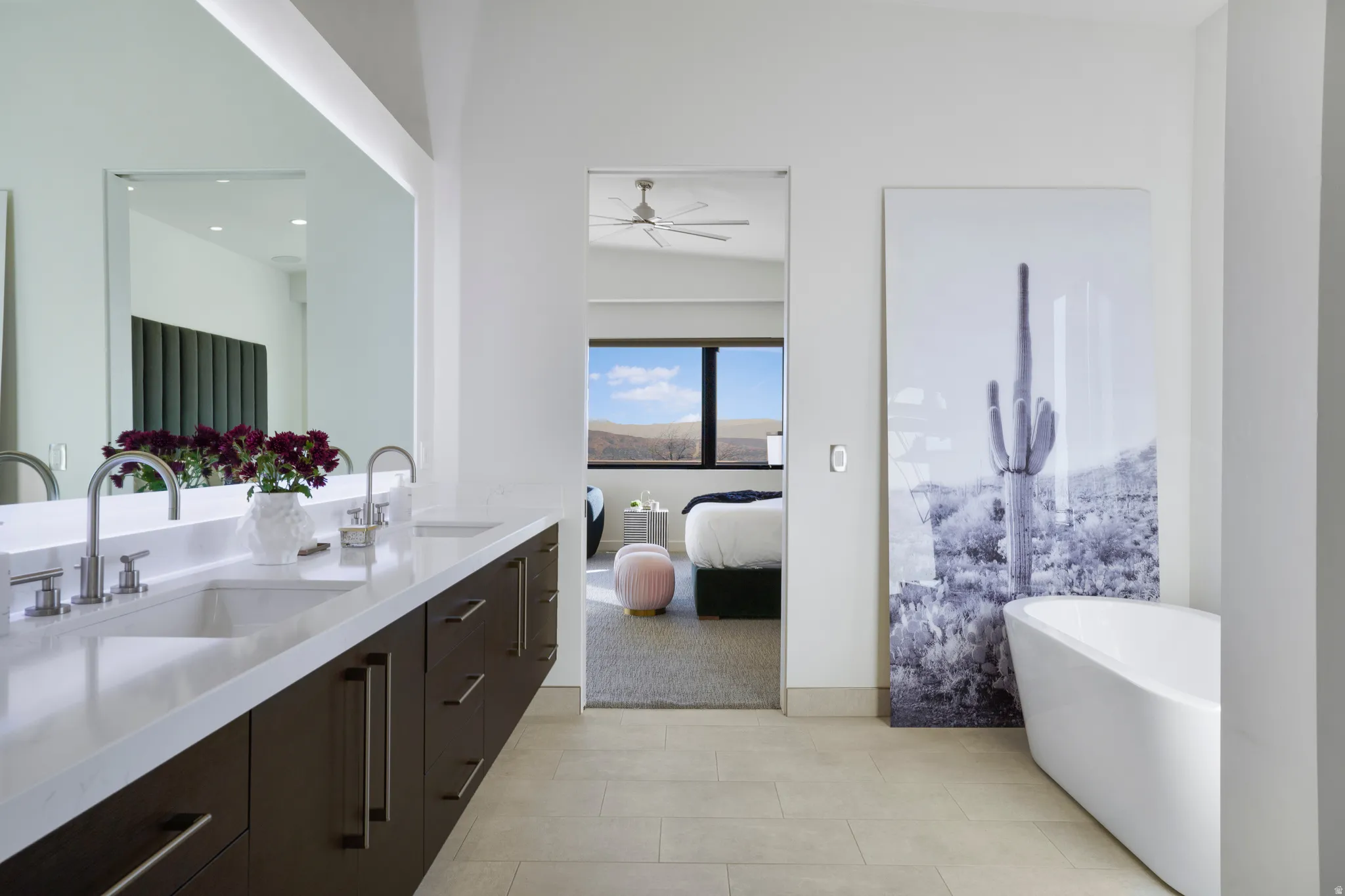 Bathroom featuring double vanity, ensuite bathroom, a freestanding tub, and light tile patterned floors