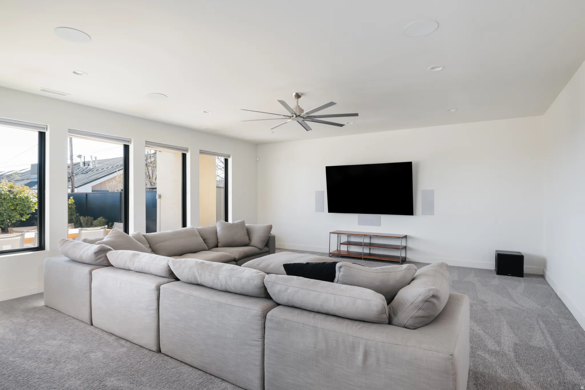 Carpeted living room featuring a ceiling fan and baseboards