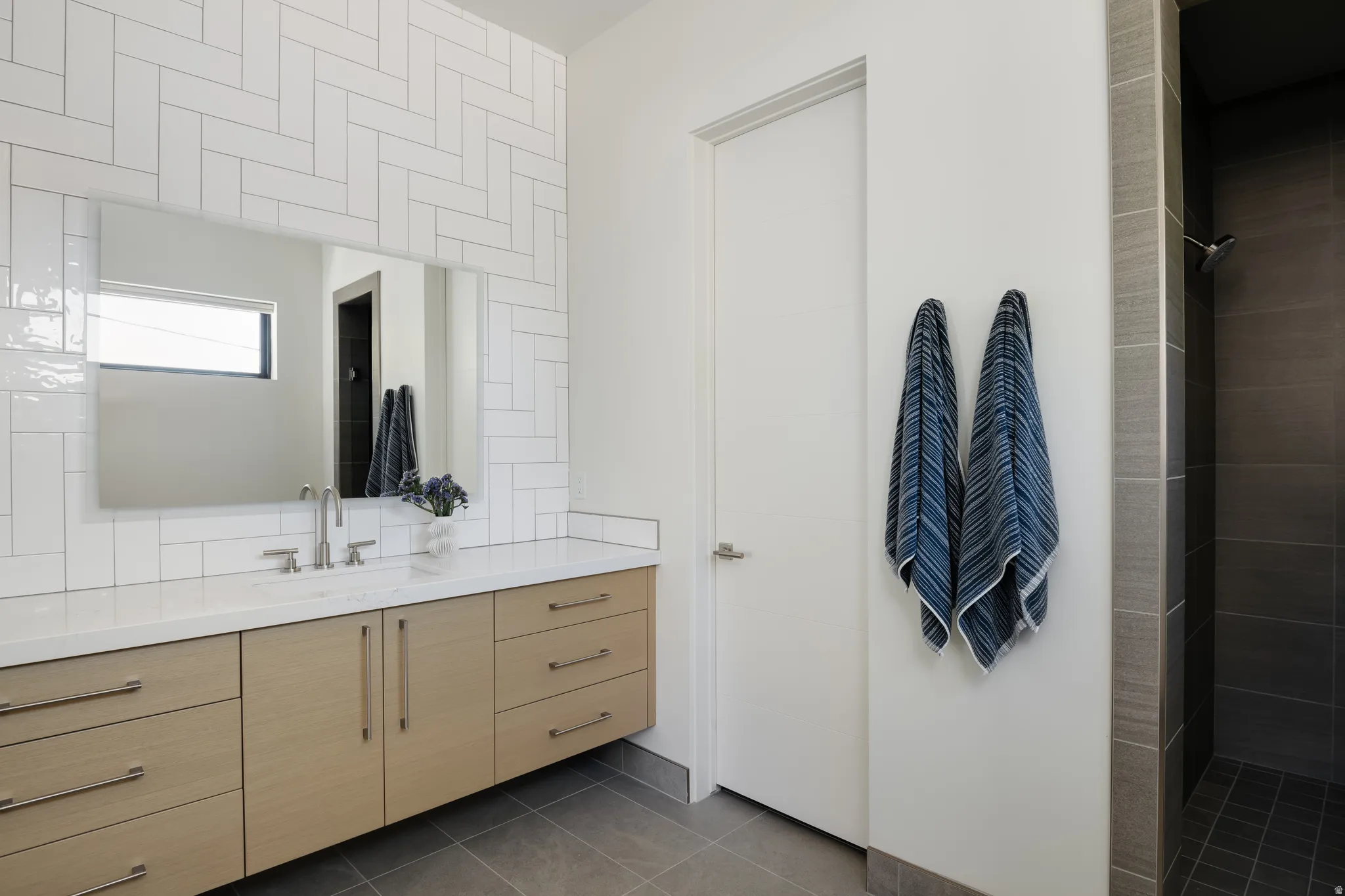 Full bathroom featuring vanity, dark tile patterned floors, and tiled shower
