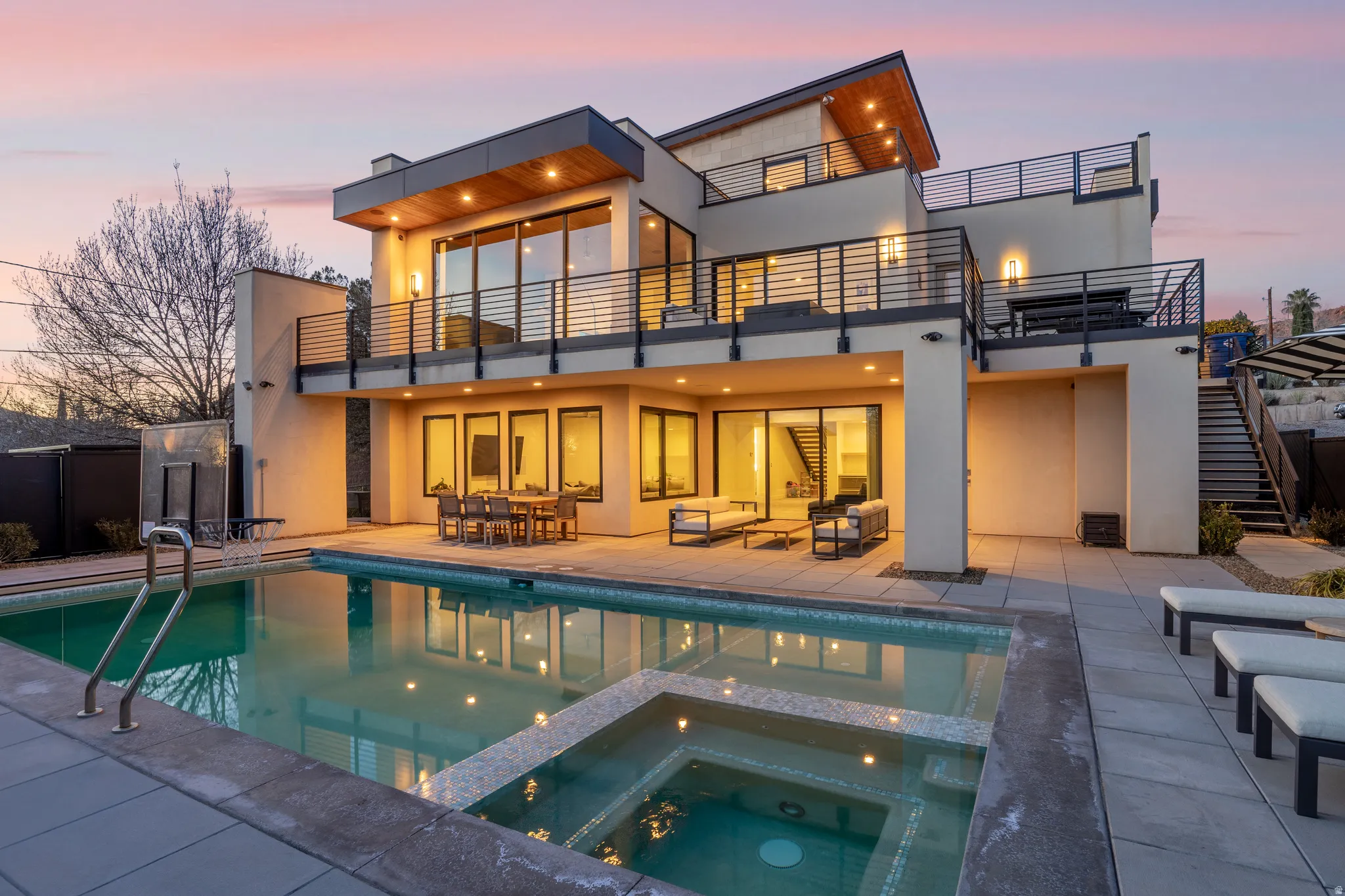 Back of property with a patio area, stucco siding, a pool with connected hot tub, and outdoor dining area