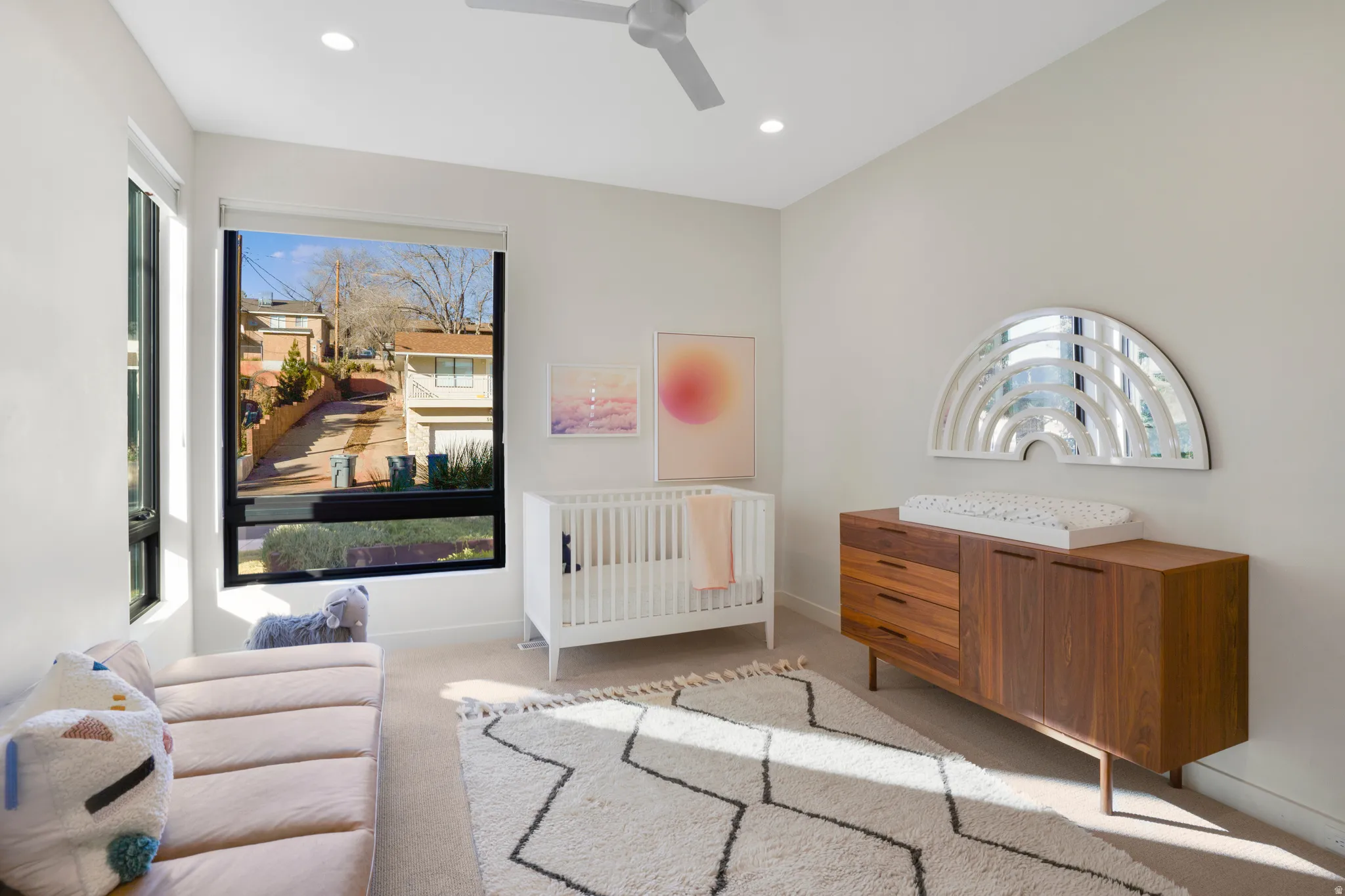Carpeted bedroom featuring a crib, ceiling fan, multiple windows, and recessed lighting