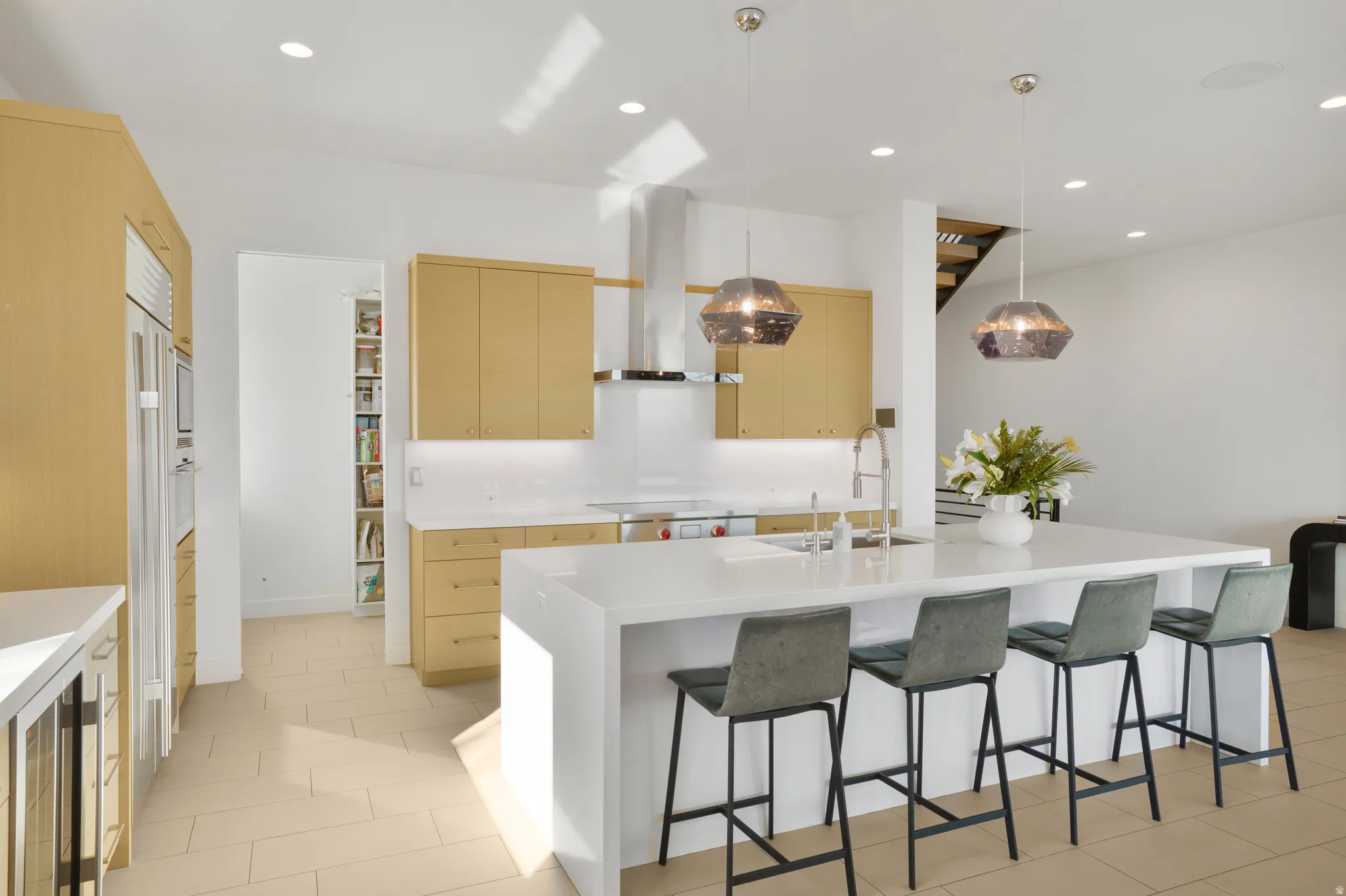 Kitchen with a breakfast bar area, decorative light fixtures, wine cooler, a kitchen island with sink, and light stone countertops