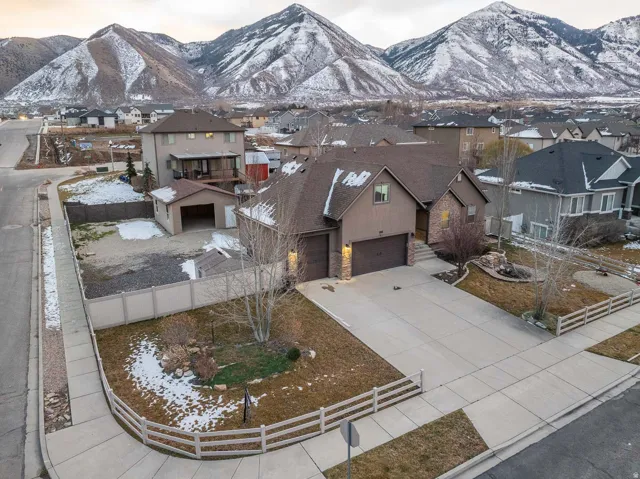 View of front of house featuring driveway, a garage, a residential view, and a mountain view