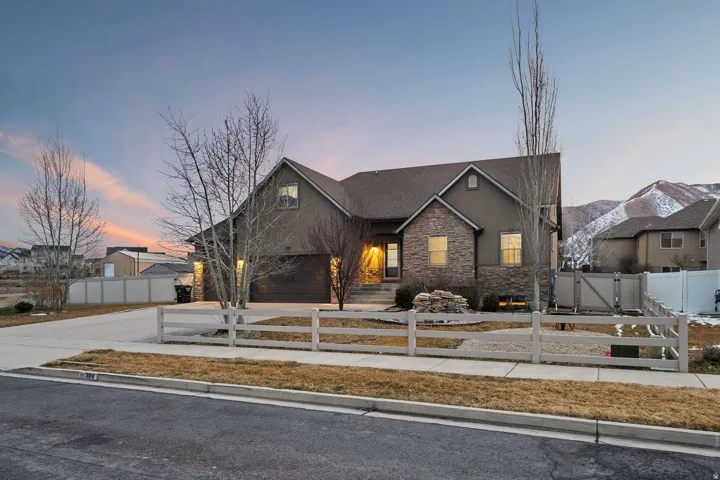 View of front of home featuring stone siding, a fenced front yard, driveway, a gate, and stucco siding