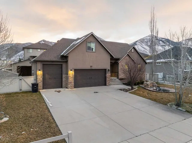 View of front of home featuring a gate, driveway, stucco siding, stone siding, and an attached garage