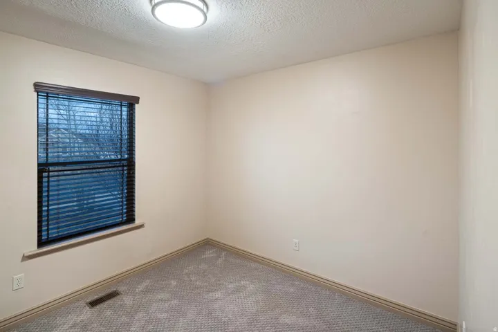 Carpeted spare room featuring a textured ceiling and baseboards