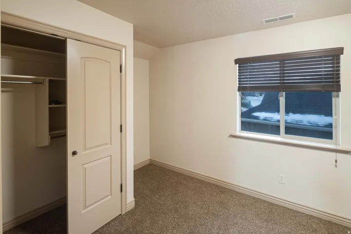 Unfurnished bedroom featuring a closet, dark carpet, and a textured ceiling