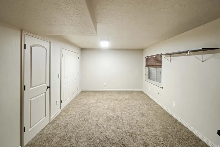 Finished basement featuring a textured ceiling and carpet floors