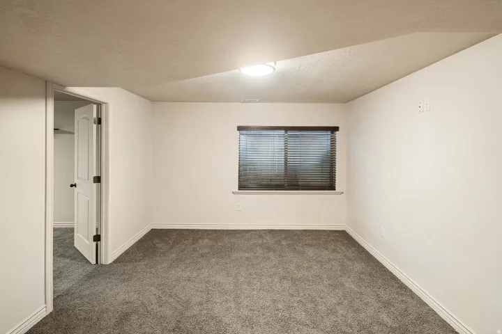 Empty room featuring a textured ceiling and dark colored carpet