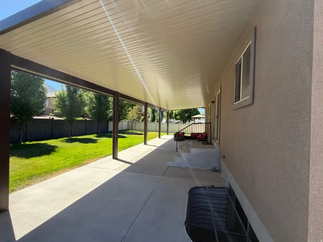 Expansive covered patio featuring a corrugated metal ceiling and structural support columns