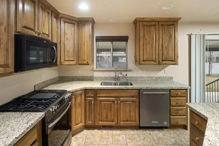 Kitchen featuring stainless steel appliances, light stone counters, wood finish cabinetry, and recessed lighting