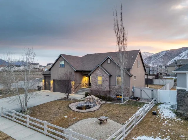 View of front facade with a gate, stone siding, concrete driveway, stucco siding, and a residential view