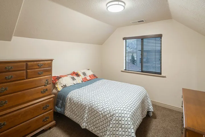 Bedroom with a textured ceiling and dark colored carpet