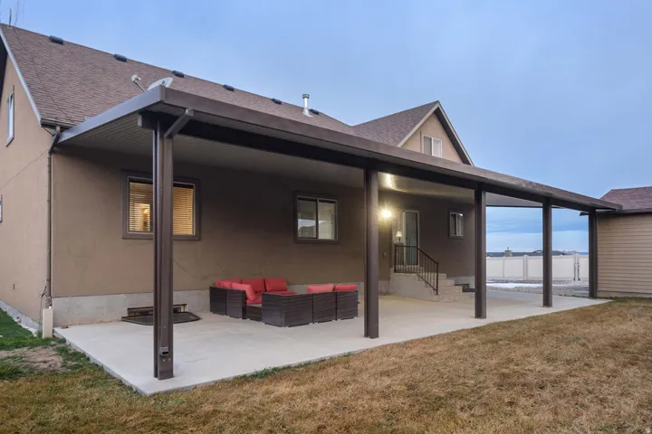Back of house featuring a patio, an outdoor living space, entry steps, stucco siding, and roof with shingles