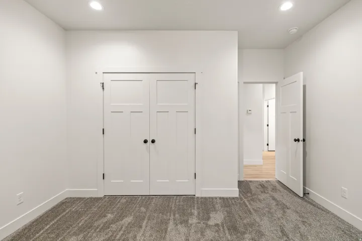 Unfurnished bedroom featuring dark colored carpet, a closet, and recessed lighting