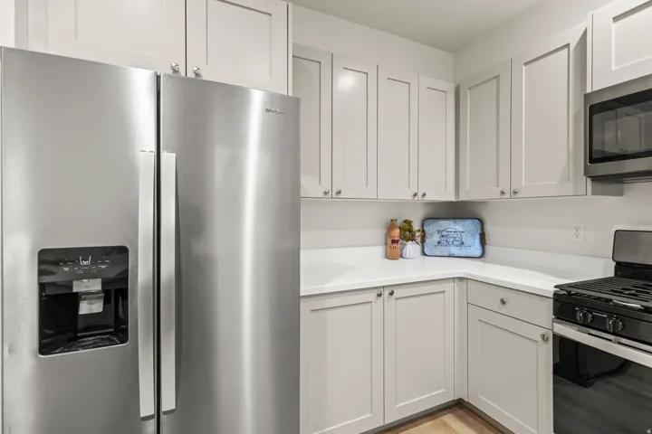 Kitchen with stainless steel appliances, white cabinets, and light wood finished floors