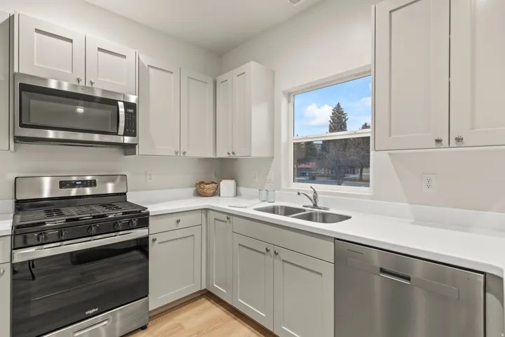 Kitchen featuring stainless steel appliances, light countertops, light wood finished floors, and white cabinets