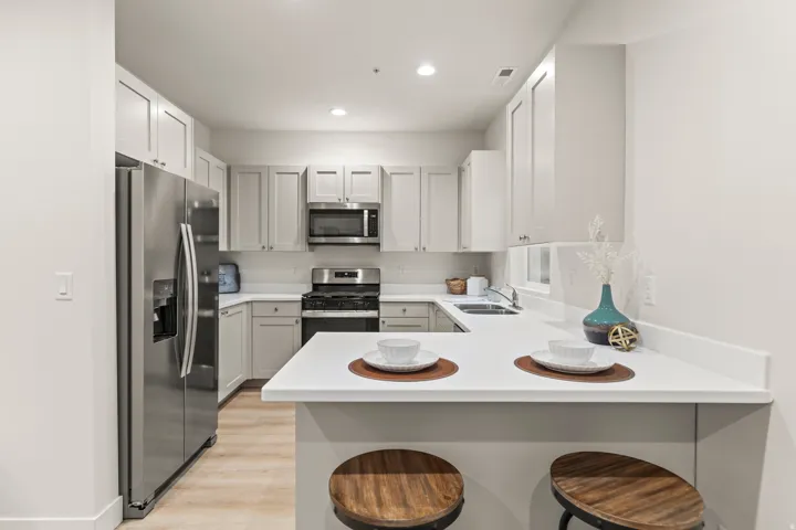 Kitchen featuring a kitchen bar, stainless steel appliances, a peninsula, light countertops, and light wood-style flooring