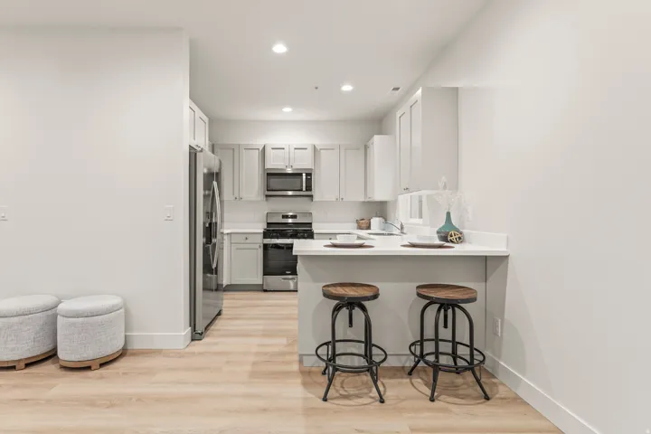 Kitchen featuring light countertops, a breakfast bar, light wood-style flooring, stainless steel appliances, and a peninsula
