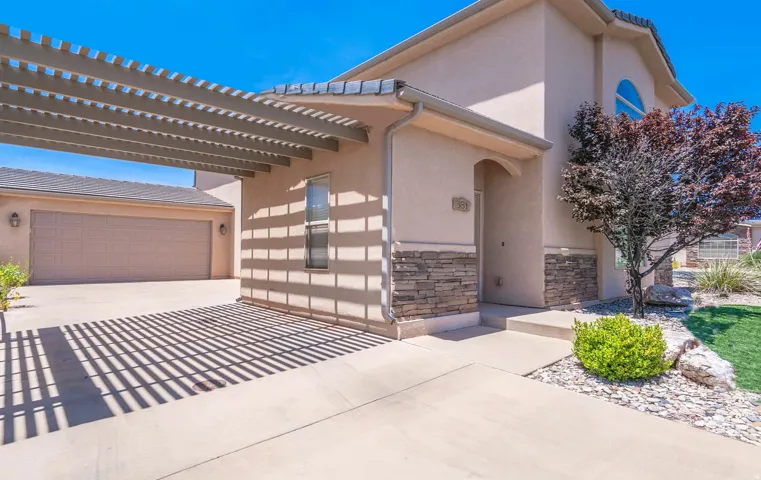 View of front of house featuring stucco siding, driveway, and stone siding
