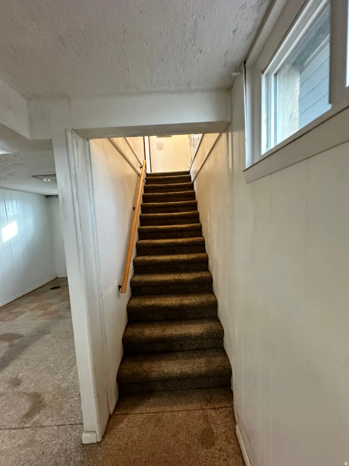 Stairs featuring a textured ceiling