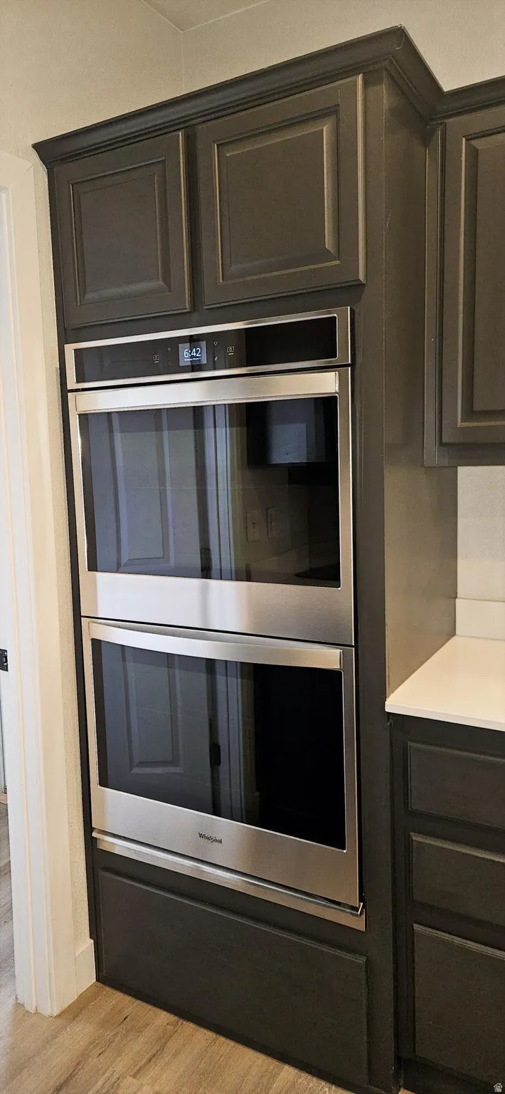 Kitchen view of double oven and light wood finished floors