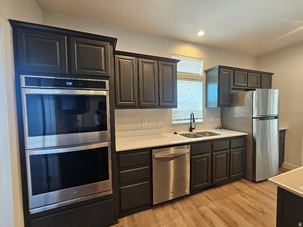 Kitchen featuring stainless steel appliances, light wood finished floors, and light countertops