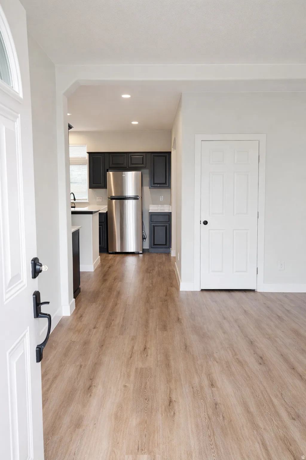 Kitchen with light countertops, freestanding refrigerator, recessed lighting, light wood-type flooring, and arched walkways