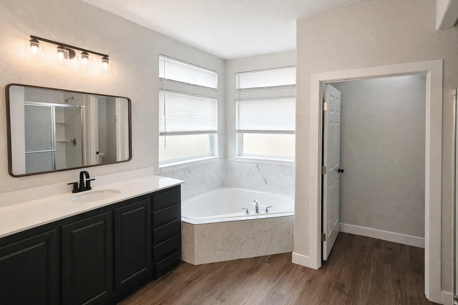 Full bathroom with a bath, dark wood-style flooring, a stall shower, and vanity