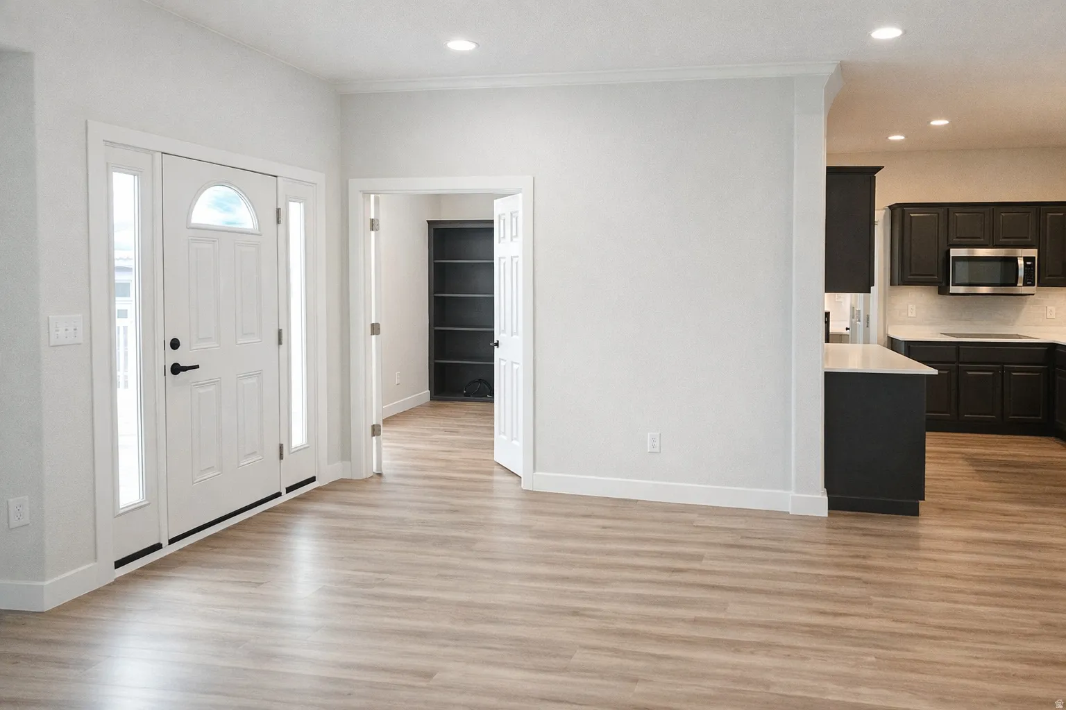 Foyer entrance with light wood finished floors, recessed lighting, and ornamental molding