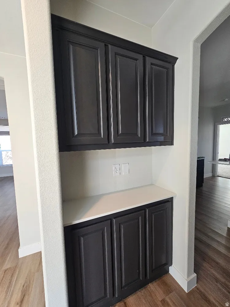 Bar area with plenty of natural light, light countertops, dark wood finished floors, and dark cabinets
