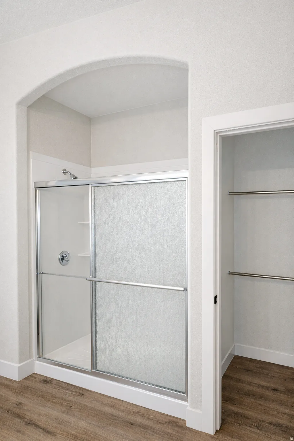 Full bathroom featuring a shower stall, dark wood-type flooring, and a walk in closet