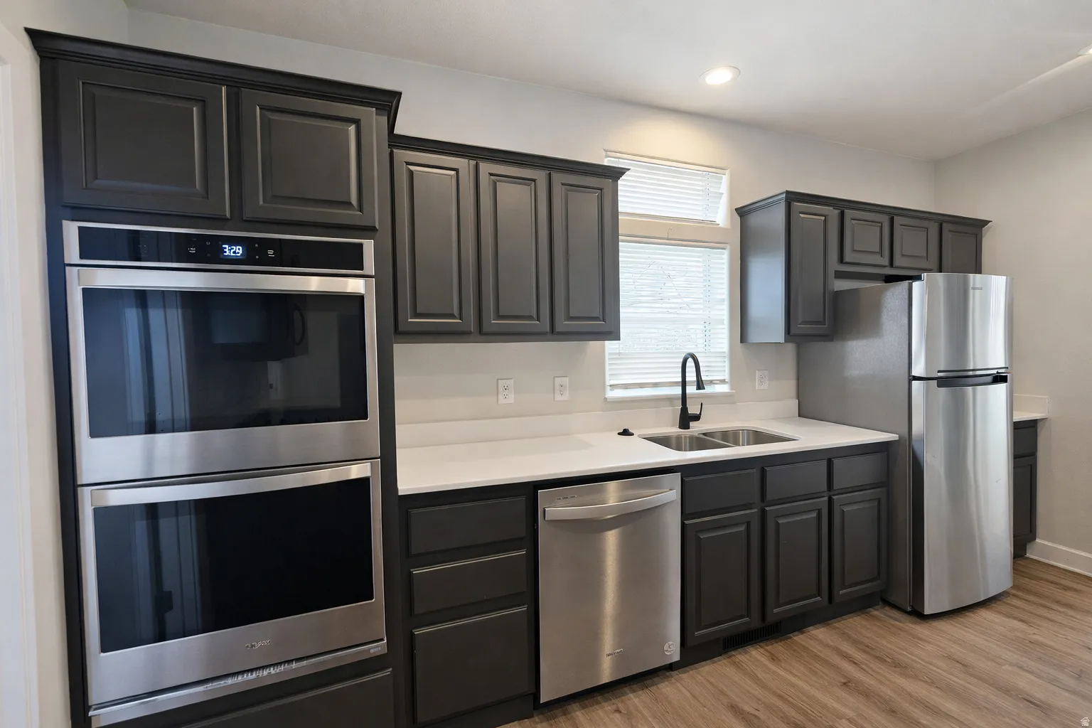 Kitchen with stainless steel appliances, light wood-style floors, and gray cabinets