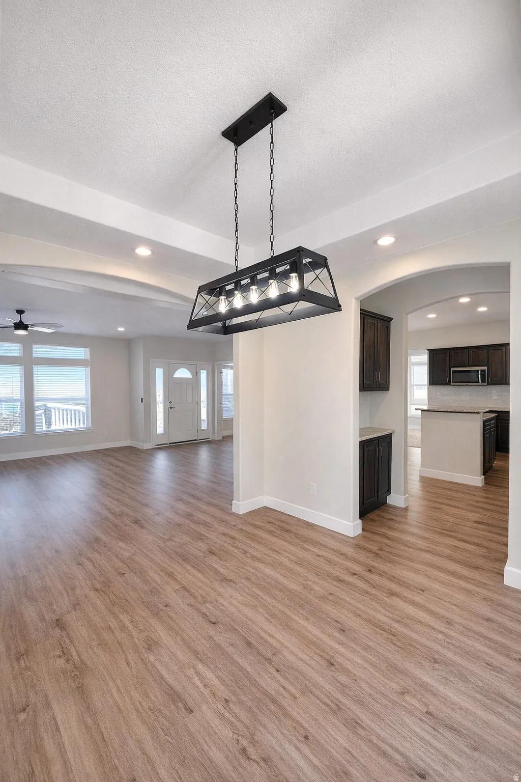 Unfurnished living room with ceiling fan, light wood finished floors, recessed lighting, and a textured ceiling