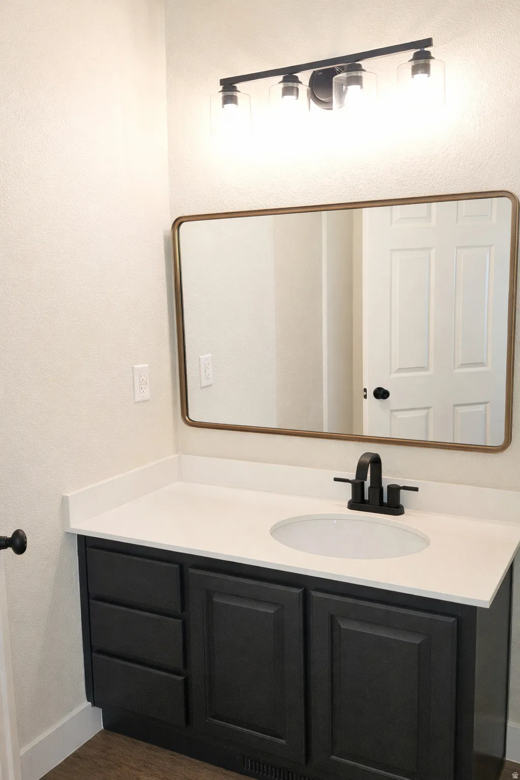 Bathroom featuring a textured wall, vanity, and dark wood finished floors
