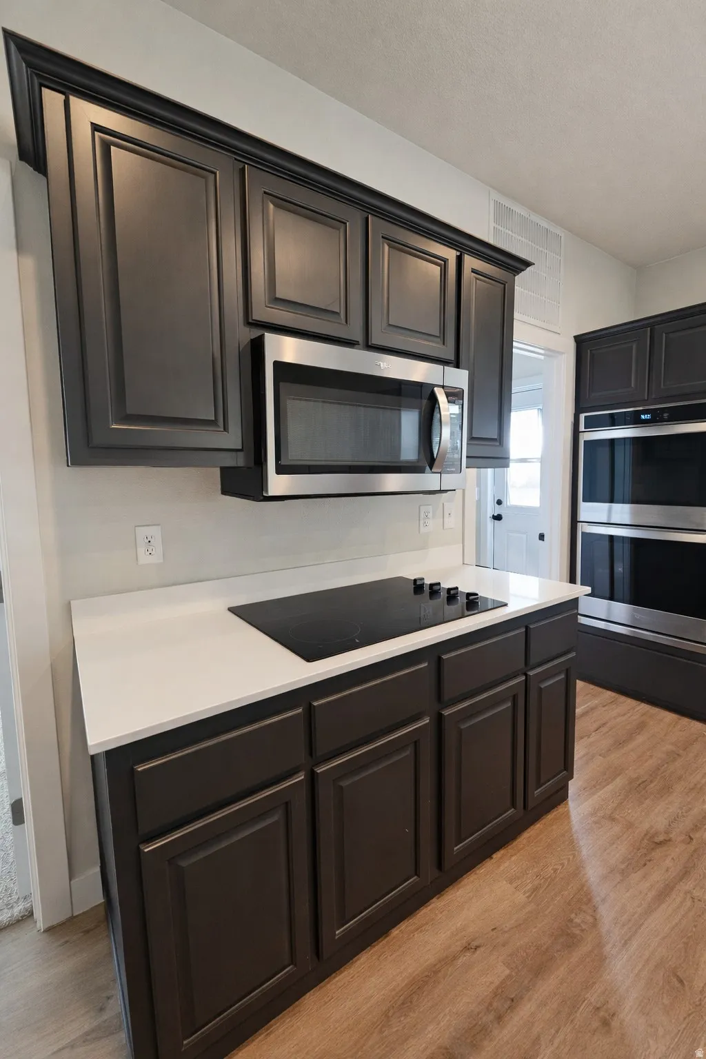 Kitchen with light wood-style flooring, stainless steel appliances, and light countertops