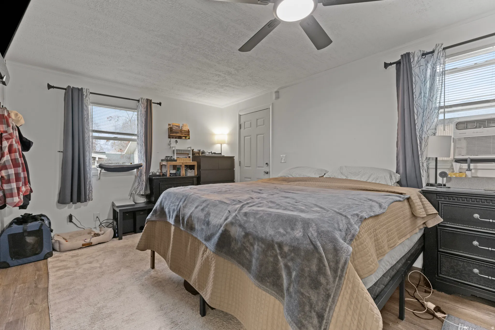 Bedroom featuring light wood-style flooring, ceiling fan, a textured ceiling, crown molding, and cooling unit