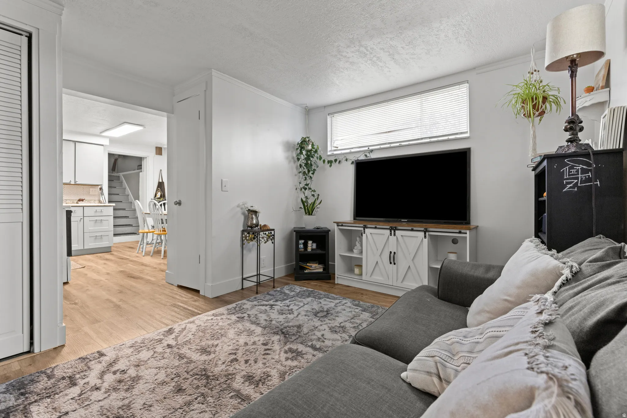 Living area featuring light wood-style floors, a textured ceiling, and ornamental molding
