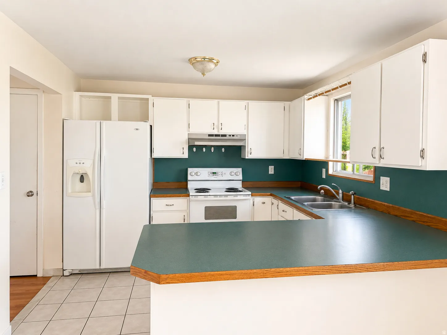 Kitchen featuring white cabinetry, a double basin sink, and a white refrigerator with an ice and water dispenser