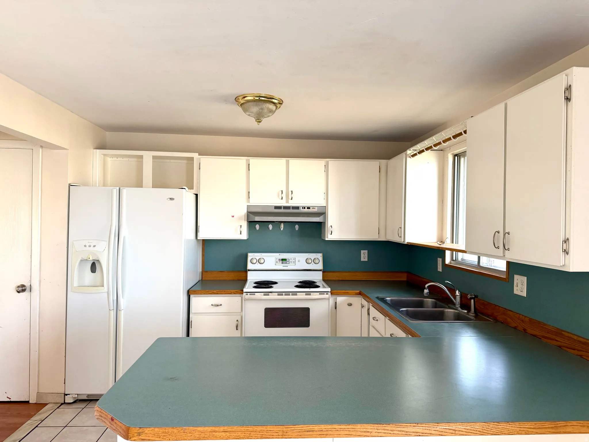 Kitchen featuring white appliances, dark countertops, and white cabinetry