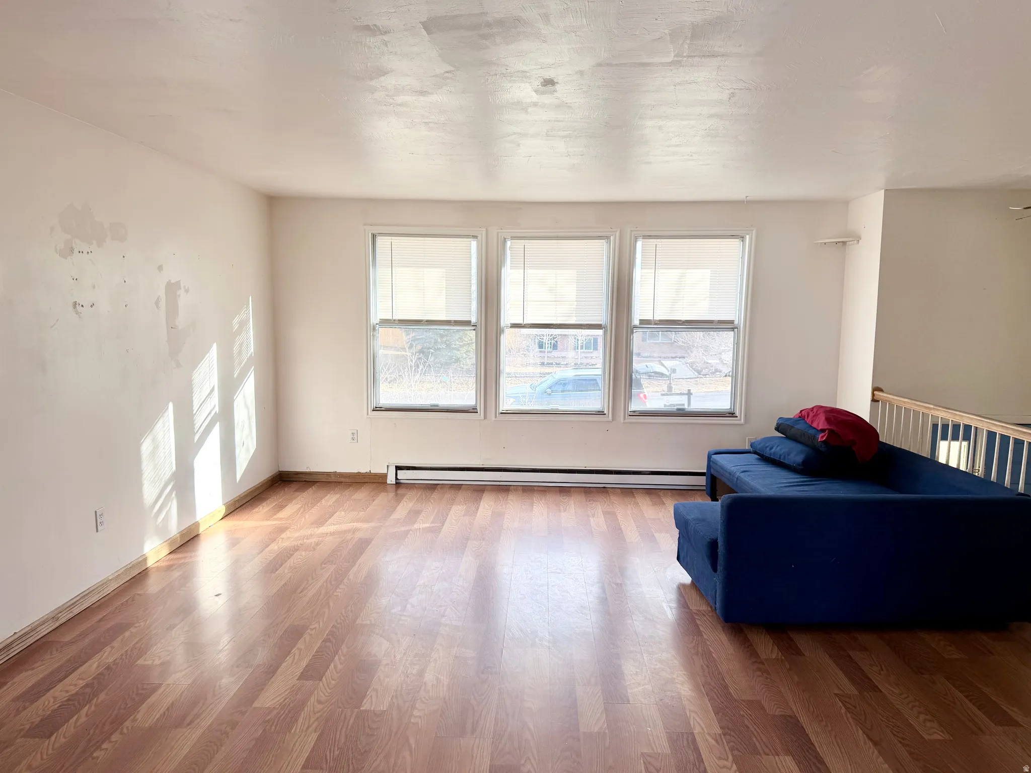 Sitting room with light wood finished floors, plenty of natural light, and baseboard heating