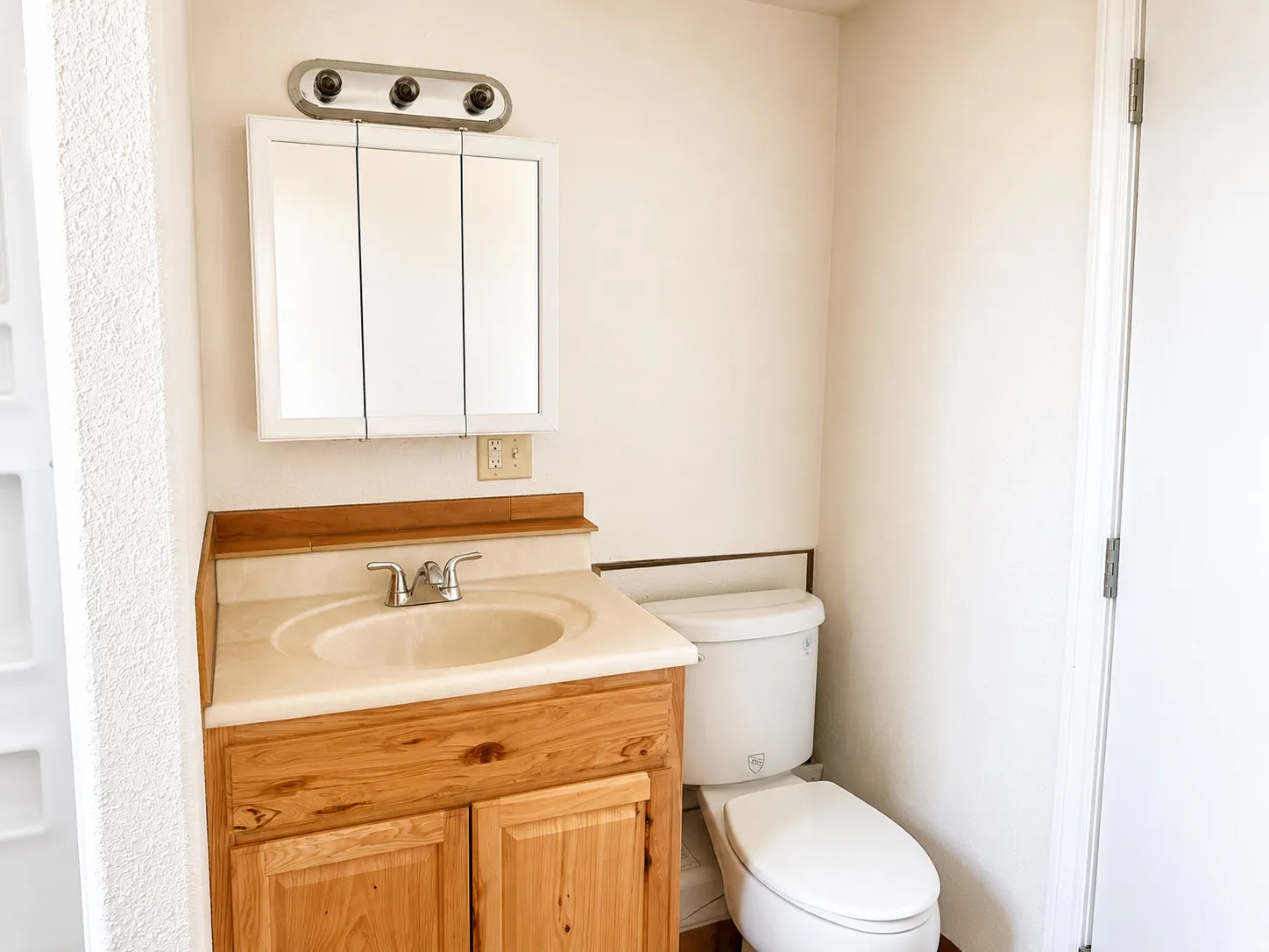 Bathroom vanity with a light wood-finish cabinet, integrated sink, and coordinating countertop