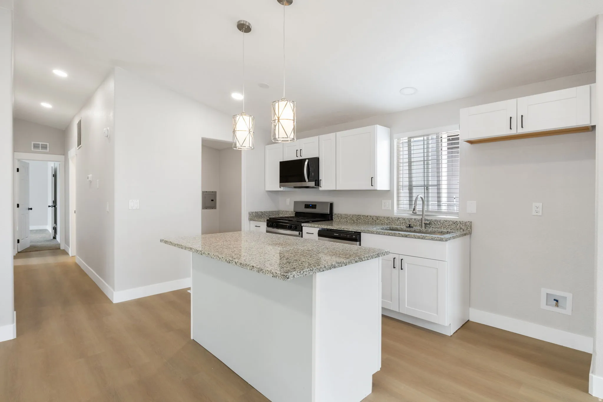 Kitchen with white cabinets, light stone countertops, and stainless steel appliances