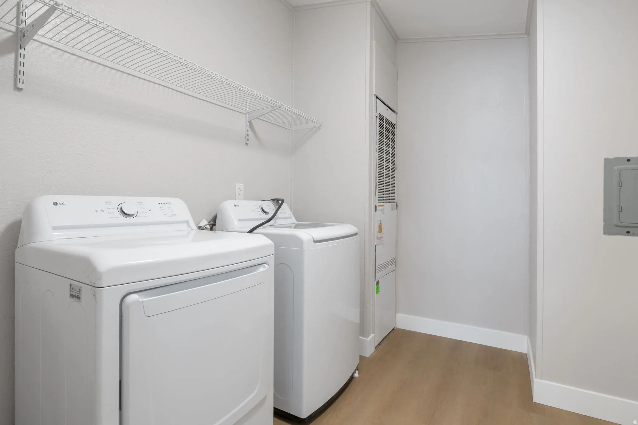Laundry room featuring light wood-style floors, washing machine and dryer, and electric panel