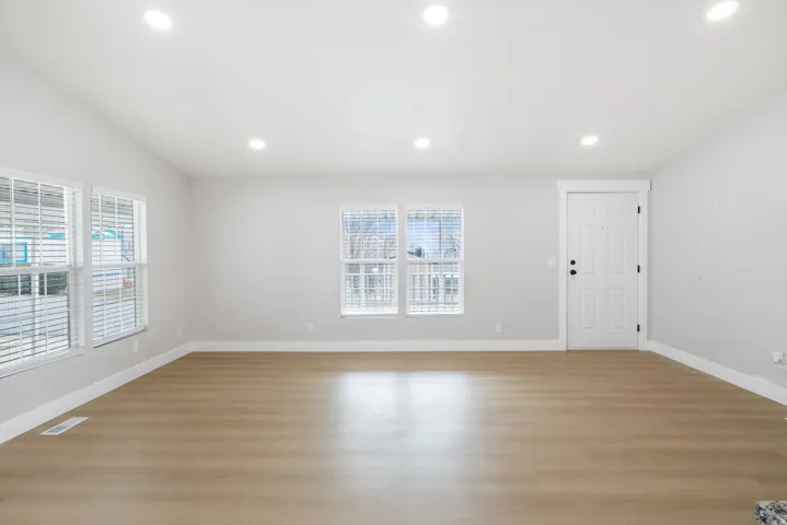 Unfurnished room with light wood-type flooring, healthy amount of natural light, recessed lighting, and lofted ceiling