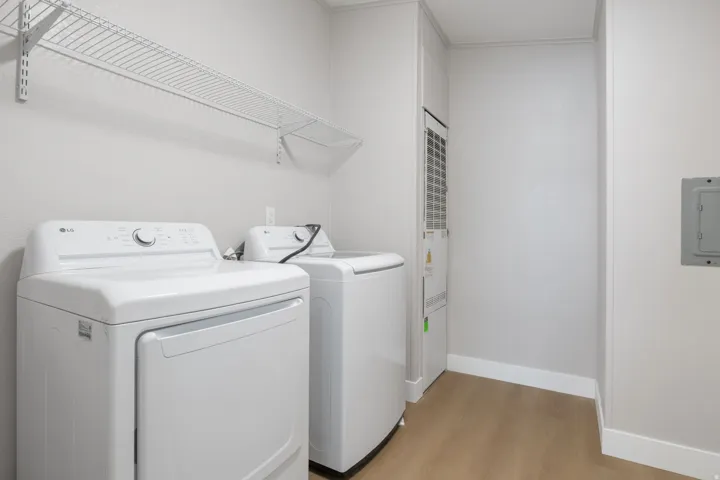 Laundry room featuring light wood-style floors, washing machine and dryer, and electric panel